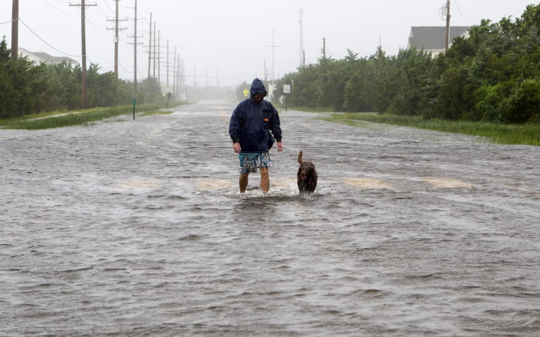 Bryan Philips walks with his dog on a flooded road in Salvo, North Carolina, as Hurricane Dorian hits the Outer Banks on September 6, 2019.