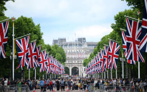 People gather of The Mall, in London, on June 1, 2022 as the Union flags flutter in the wind ahead of the Platinum Jubilee's celebrations for Britain's Queen. - Britain's Queen Elizabeth II has been on the throne since she was 25, an ever-present figure for the lives of most people in Britain, as well as one of the most recognisable people around the world. She will celebrate her Platinum Jubilee over four days from Thursday June 2nd, for her 70 years of reign. (Photo by Daniel LEAL / AFP)