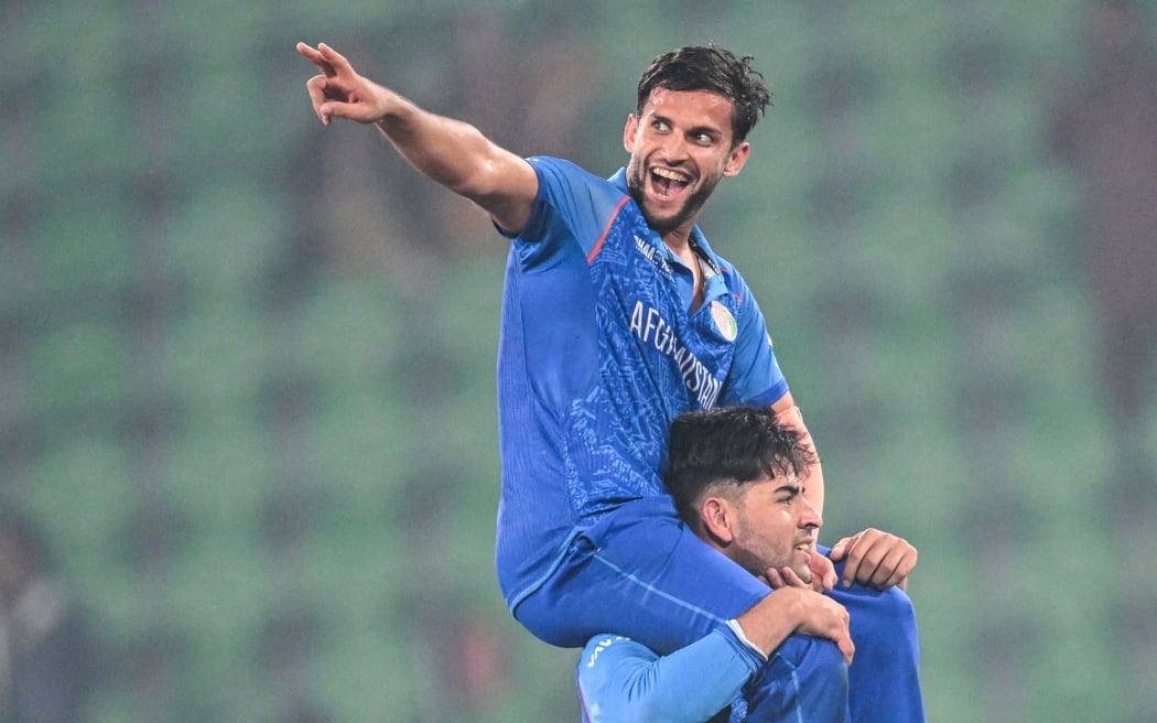Afghanistan's Azmatullah Omarzai (top) celebrates Afghanistan's victory over England at the Champions Trophy, 2025.