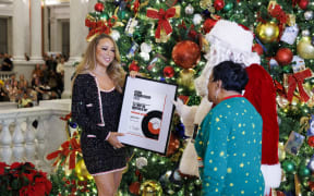 Librarian of Congress Carla Hayden and Santa Claus present pop superstar Mariah Carey with a framed certificate honoring her induction into the 2023 Library of Congress National Recording Registry for "All I Want for Christmas is You," December 14, 2023. Photo by Shawn Miller/Library of Congress.