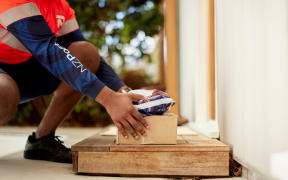 An unidentified NZ Post worker is delivering two parcels onto a doorstep.