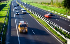 A file photo shows blurred cars on a four-lane highway.