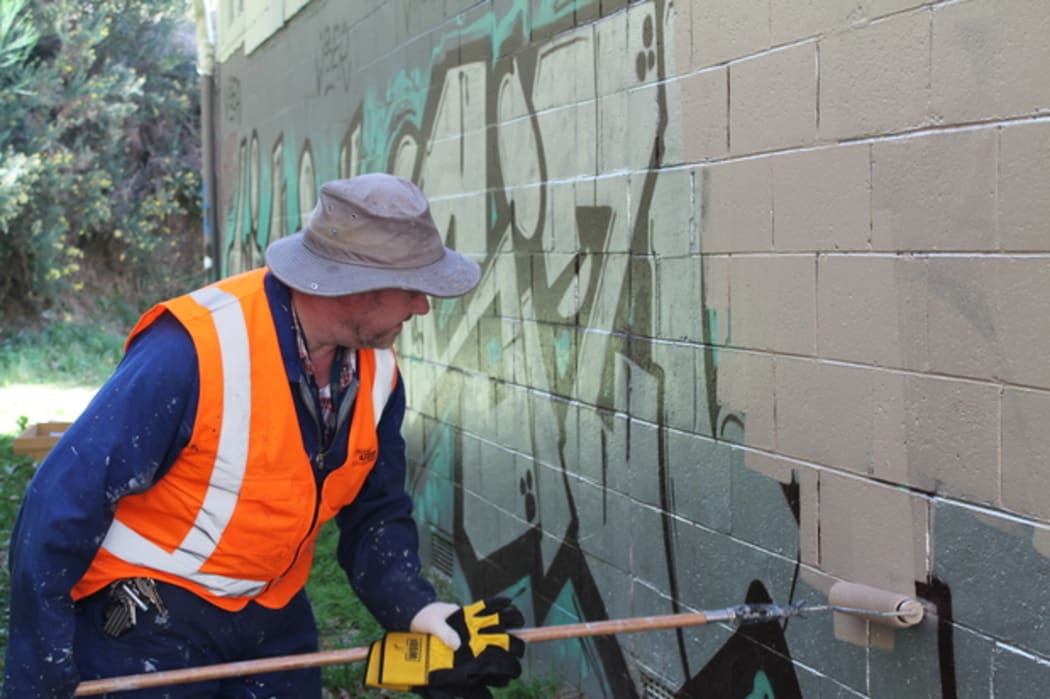 Man cleaning up graffiti.