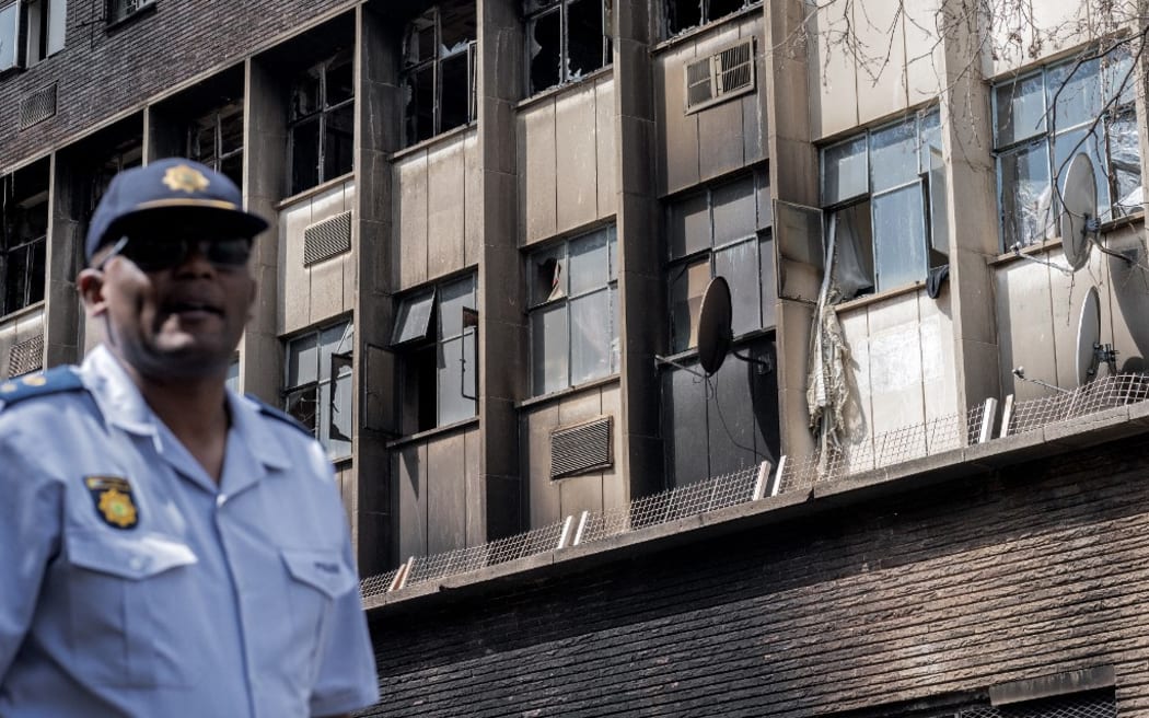 A South African police officer stands at the scene of the burned apartment block in Johannesburg.