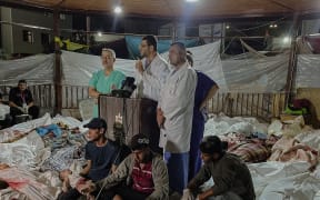 Amid the tragic aftermath of the bombing of Gaza's Al-Ahli Baptist Hospital on October 17, 2023, doctors at Al-Shifa Hospital gather to make a press statement, surrounded by Palestinian bodies. Photo by Mohamed Masri / Middle East Images / Middle East Images via AFP