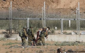 Israeli soldiers carry away an injured Palestinian who tried to approach the border fence east of Jabalia in the northern Gaza Strip on June 27, 2018.