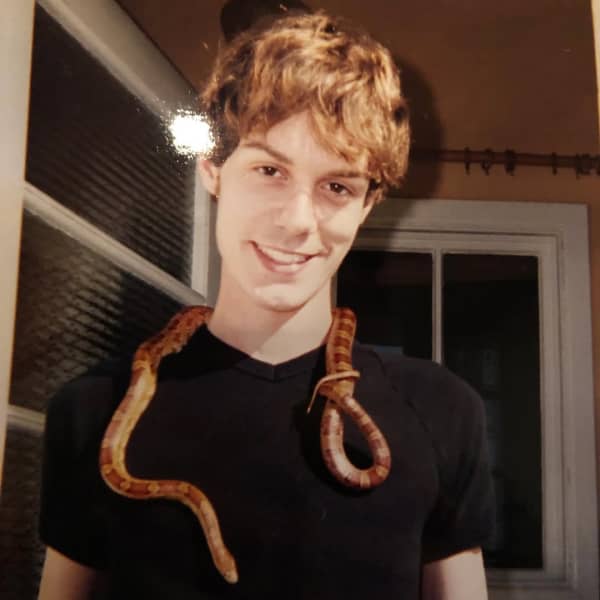 Tony Stamp is a young smiling man with orangey hair, a black tshirt and a brown snake around his neck.