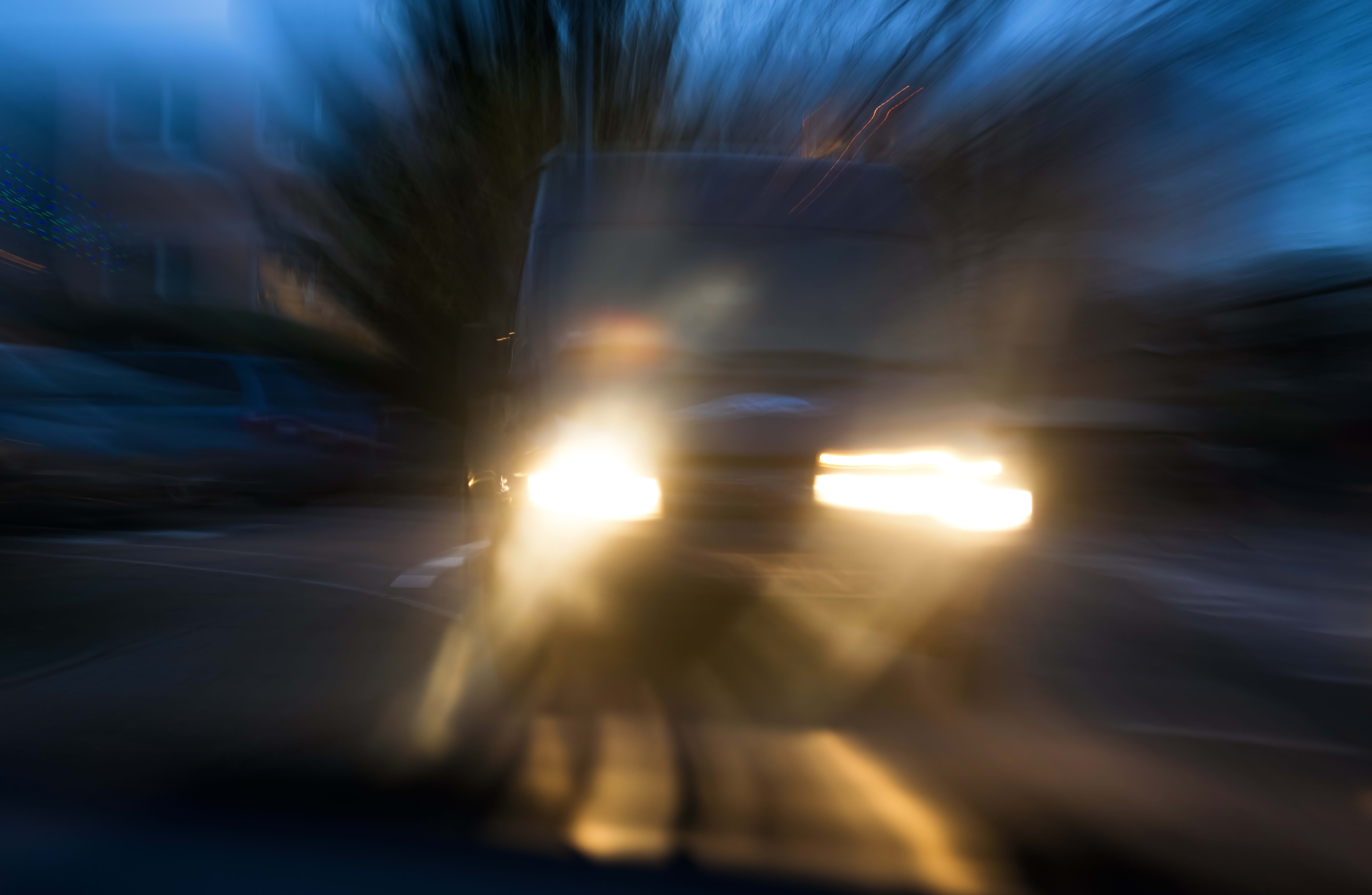 A vehicle approaches in semi-darkness under dangerous conditions.