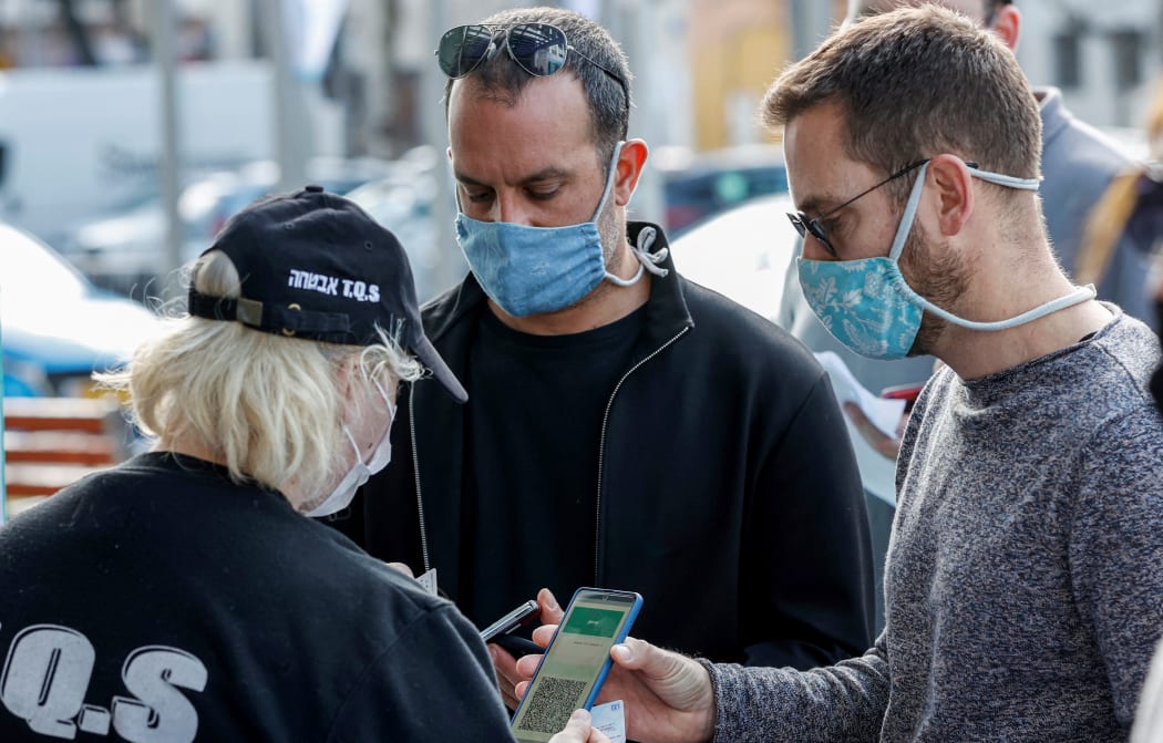Attendees present their "green passes" (proof of being fully vaccinated against COVID-19 coronavirus disease) as they arrive at Bloomfield Stadium in the Israeli Mediterranean coastal city of Tel Aviv on March 5, 2021,