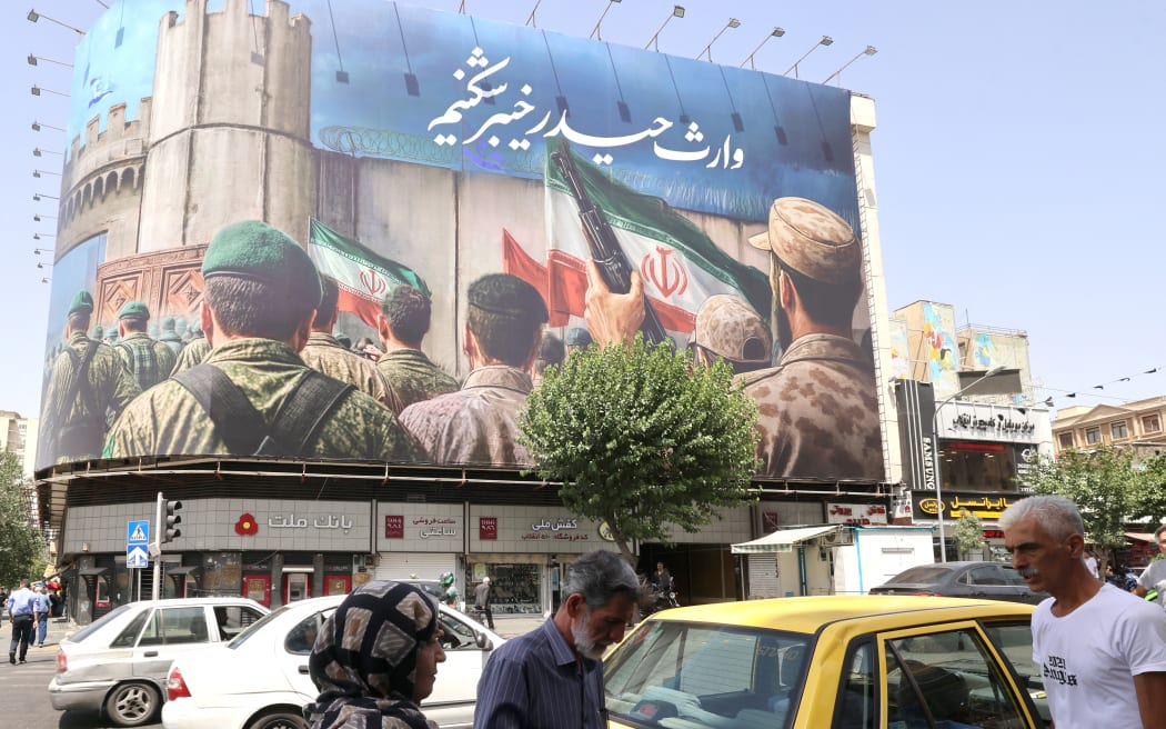 People walk past a huge banner on Enghelab (Revolution) Square, in Tehran on June 24.