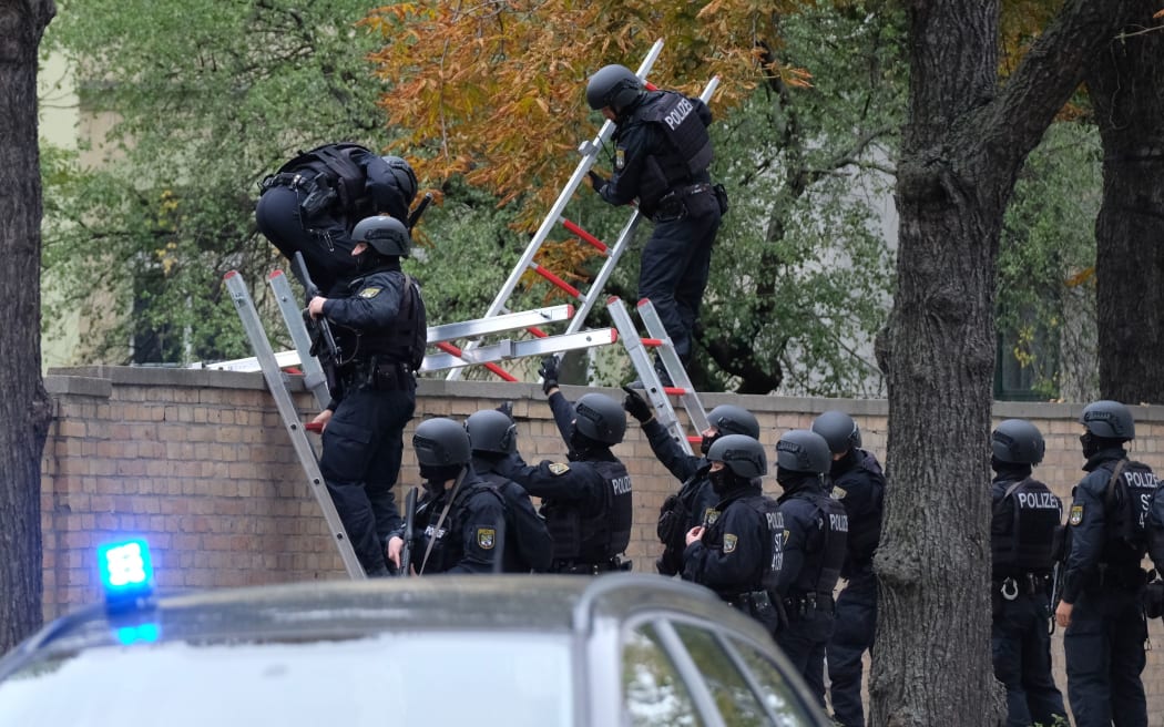 Policemen climb over a wall of the Jewish cemetery close to the site of a shooting in Halle an der Saale, eastern Germany, on October 9, 2019.
