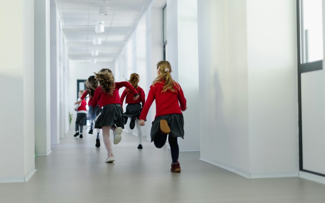Children wearing uniform running in school corridor.
