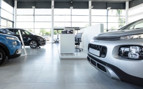 Car seller's station and parked cars in the interior of a modern dealership