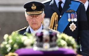 Britain's King Charles III walks behind the coffin of Queen Elizabeth II, adorned with a Royal Standard and the Imperial State Crown and pulled by a Gun Carriage of The King's Troop Royal Horse Artillery, during a procession from Buckingham Palace to the Palace of Westminster, in London on September 14, 2022. - Queen Elizabeth II will lie in state in Westminster Hall inside the Palace of Westminster, from Wednesday until a few hours before her funeral on Monday, with huge queues expected to file past her coffin to pay their respects. (Photo by Marco BERTORELLO / AFP)