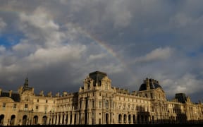 (FILES) A rainbow emerges over the Louvre museum, bathed in late afternoon sunlight, in Paris, on December 6, 2025. A water leak on November 26, 2025 damaged several hundred items in the Louvre's Egyptian Antiquities library, the Paris museum told AFP on December 7, 2025, confirming a report by La Tribune de l'Art. (Photo by Ian LANGSDON / AFP)