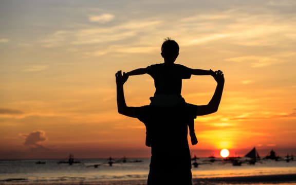 father and son on sky at sunset beach