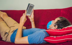 E-book and online education. A man is reading a quarantined book at home. A man in a medical mask remained at home in self-isolation.