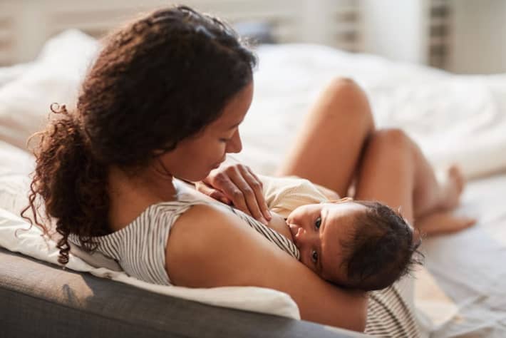 A darkhaired mother breastfeeds her darkhaired baby