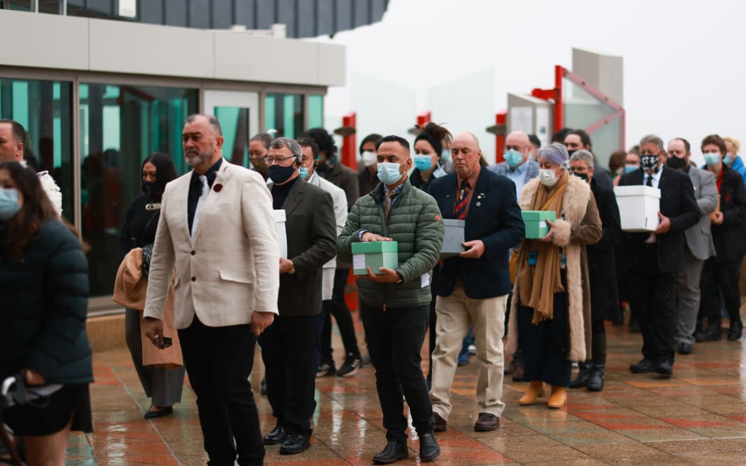 A procession of people carry boxes into Te Papa. They are returning skeletal remains of Moriori to New Zealand from where they were held overseas.