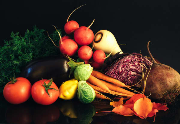 An array of vegetables including tomato, brussel sprouts, carrots, radish, cabbage and beetroot.