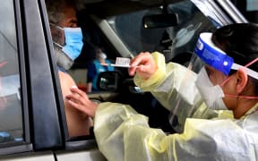 A resident receives a dose of the Pfizer Covid-19 vaccine in Australia's first drive through vaccination centre in the outer Melbourne suburb of Melton on August 10, 2021.