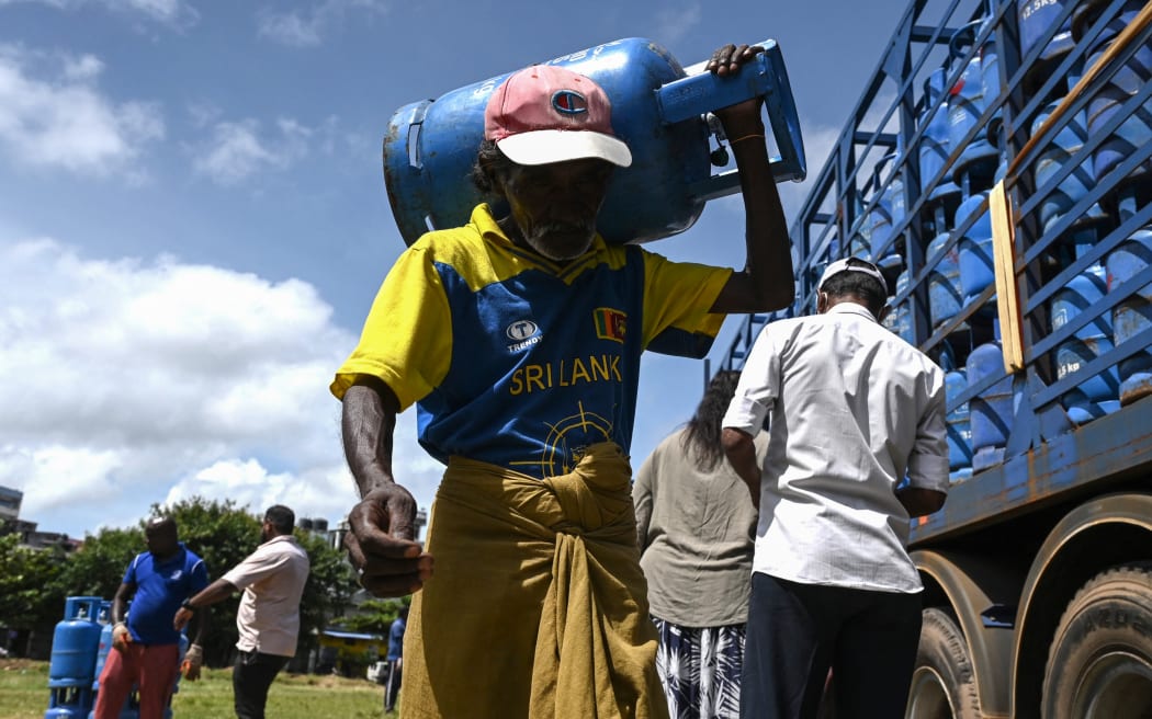 A man carries a liquefied petroleum gas cylinder after collecting it at distribution point in Colombo on 12 July 2022.