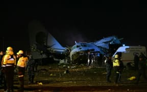 Members of the armed forces stand guard next to the wreckage of a military plane that crashed in el Alto, near La Paz on February 27, 2026. At least 11 people were killed on February 27 when a Bolivian military cargo plane carrying banknotes crashed while landing near the capital city La Paz, prompting police to repel bystanders grabbing cash. (Photo by AIZAR RALDES / AFP)