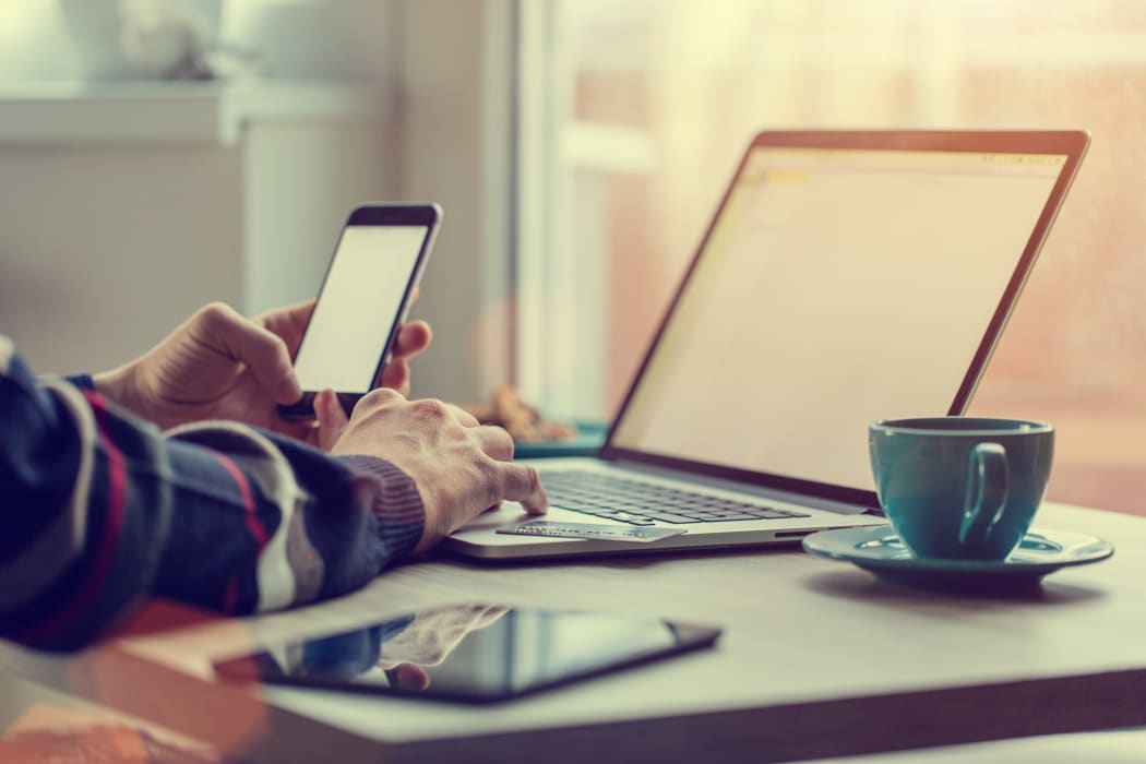 Man working on notebook, with a fresh cup of tea or coffee. Home work concept.