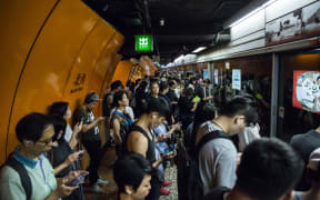 Commuters line up on a Mass Transit Railway (MTR) platform in Hong Kong on 30 July, 2019, after MTR services were resumed after being suspended by protesters demonstrating against a controversial extradition bill.