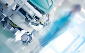 Medical bed in hospital hallway with professionals hurrying to the emergency case