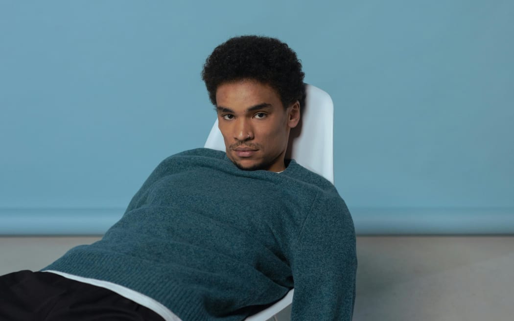 A man in a blue sweatshirt slouching on a chair