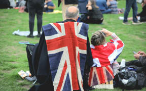 People in Hyde Park preparing to watch the funeral of Queen Elizabeth II on a big screen.