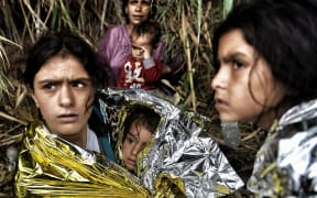 Syrian refugees are covered with life blankets upon arriving to the Greek island of Lesbos, after crossing the Aegean sea from Turkey, on September 28, 2015.