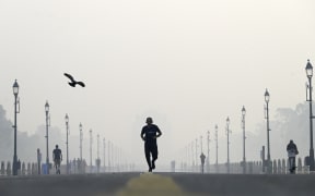 A man jogs along the road in front of India Gate amid smoggy conditions in New Delhi on November 1, 2022. (Photo by Money SHARMA / AFP)