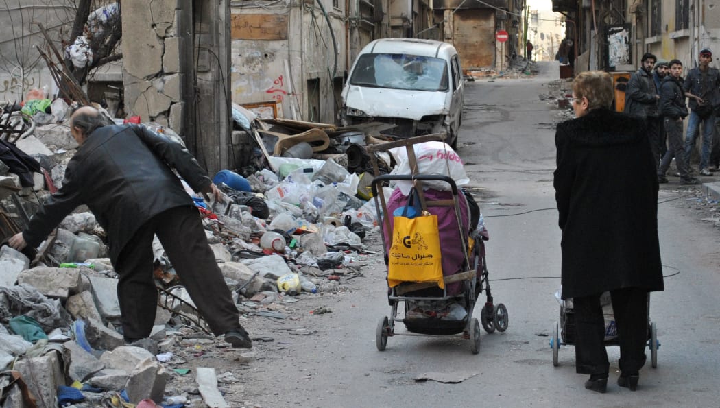 A man looking for items to scavenge amid debris and garbage in a street in a rebel area of Homs.