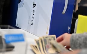 A customer buys the new Sony PlayStation 5 gaming console on the first day of its launch, at an electronics shop in Kawasaki, Kanagawa prefecture on November 12, 2020. (Photo by CHARLY TRIBALLEAU / AFP)