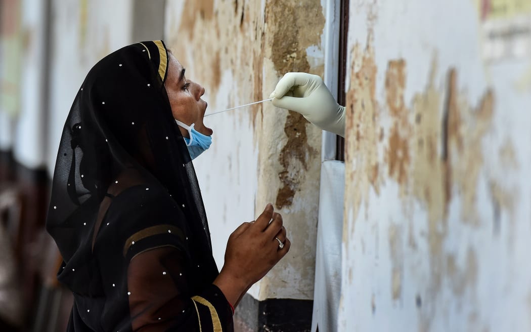 A health official takes a swab sample from a woman to test for the Covid-19 coronavirus at a testing point in Allahabad, India