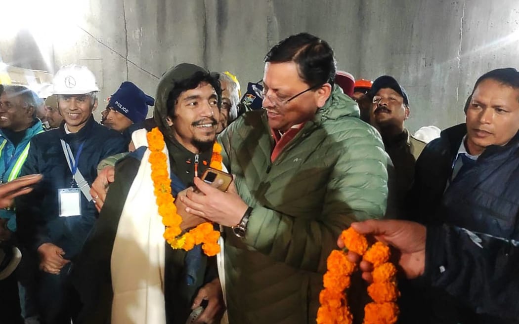 This handout picture released by Uttarakhand's Department of Information and Public Relation (DIPR) and taken on November 28, 2023, shows a contruction worker (front 2L) interacting with Chief minister of Uttarakhand Pushkar Singh Dhami (R) following his rescue from inside the under construction Silkyara tunnel during a rescue operation for trapped workers after a section of the tunnel collapsed in the Uttarkashi district of India's Uttarakhand state. Indian rescuers on November 28 began bringing out the first of the 41 men trapped for 17 days behind tonnes of earth inside a Himalayan road tunnel after a marathon engineering operation to free them. (Photo by Department of Information and Public Relation (DIPR) Uttarakhand / AFP) / RESTRICTED TO EDITORIAL USE - MANDATORY CREDIT "AFP PHOTO /  Department of Information and Public Relation (DIPR) Uttarakhand " - NO MARKETING NO ADVERTISING CAMPAIGNS - DISTRIBUTED AS A SERVICE TO CLIENTS