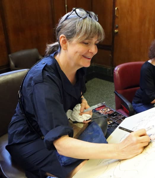 Elizabeth Williams with glasses on her head, sketching in court.