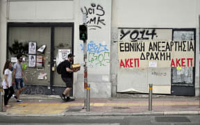People walk past closed businesses in central Athens.