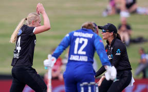 New Zealand's Hannah Rowe and Melie Kerr celebrate the wicket of England's Tammy Beaumont.