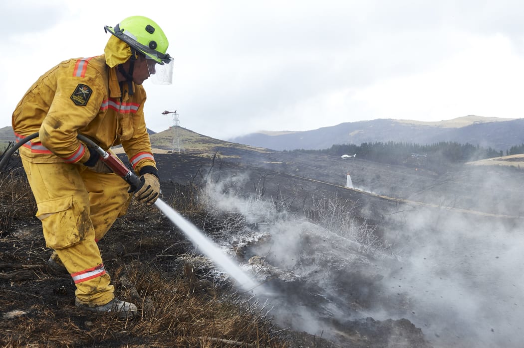 Fire fighter Lieutenant Oli Barnfather of the New Zealand Army fights an underground hotspot on the Port Hills of Christchurch.