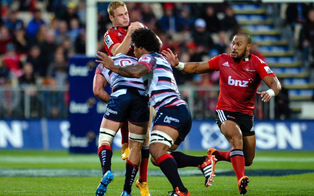 Johnny McNicholl of the Crusaders is tackled by Sean McMahon and Lopeti Timani of the Rebels.