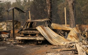 A damaged home and car in a mobile home park destroyed by fire on 10 September 2020 in Phoenix, Oregon.
