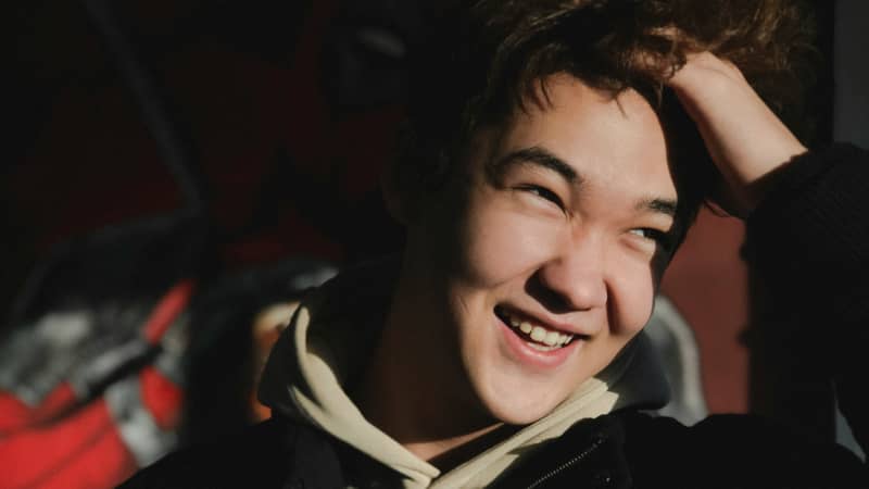 A young men smiles with the sun in his face.