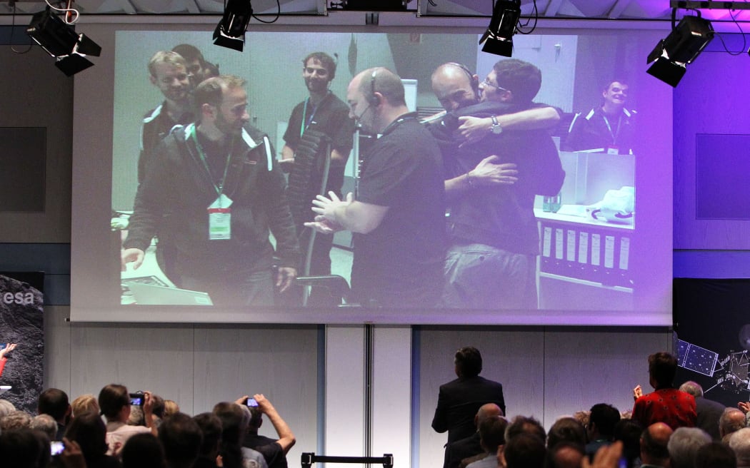 Engineers and scientists react in the main control room of the European Space Operation Center after the controlled descent of Rosetta onto the surface of Comet 67P/Churyumov-Gerasimenko.