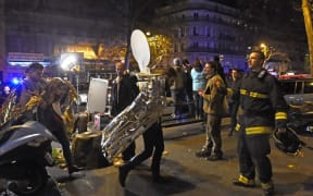 People wearing survival blankets walk by a rescuer near the Bataclan concert hall in central Paris,