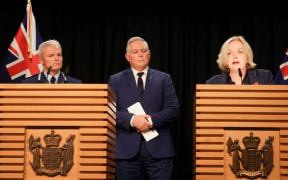 Public Services Minister Judith Collins speaks after a damning report into police conduct, with Police Commissioner Richard Chambers and Police Minister Mark Mitchell in the background.