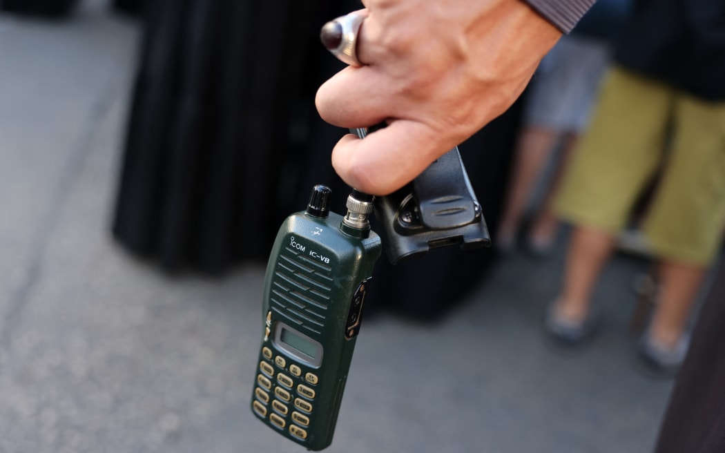 A man holds a walkie talkie device after he removed the battery during the funeral of persons killed when hundreds of paging devices exploded in a deadly wave across Lebanon the previous day, in Beirut's southern suburbs on September 18, 2024. Hundreds of pagers used by Hezbollah members exploded across Lebanon on September 17, killing at least nine people and wounding around 2,800 in blasts the Iran-backed militant group blamed on Israel. (Photo by ANWAR AMRO / AFP)
